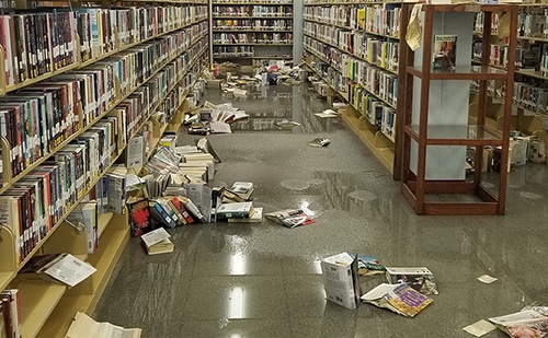 Wet library books displaced off bottom shelves by floodwaters.