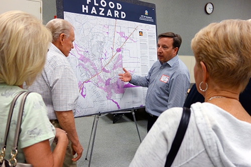People standing at a poster-size map of flood hazard.