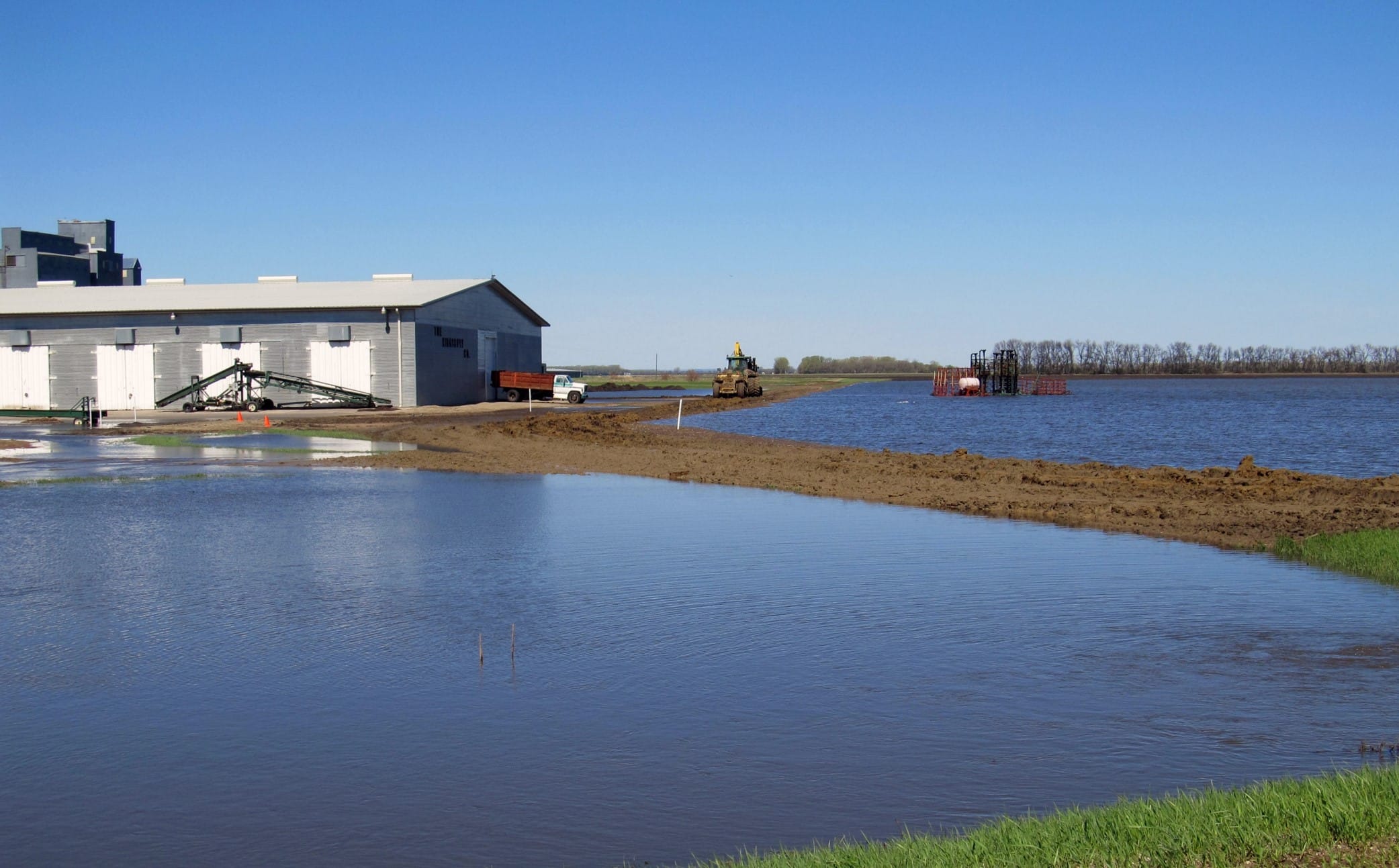 Agricultural building elevated on fill with water ponded in front.
